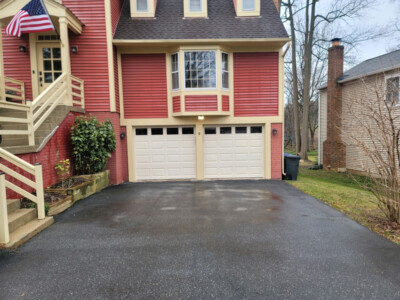 2 Story home with red siding, wood trim and garage with white doors